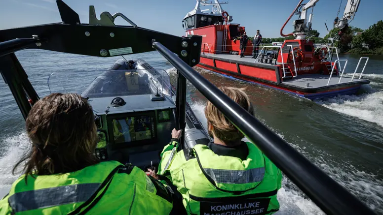 Marechaussees in een vaartuig met een boot van de brandweer op de achtergrond.
