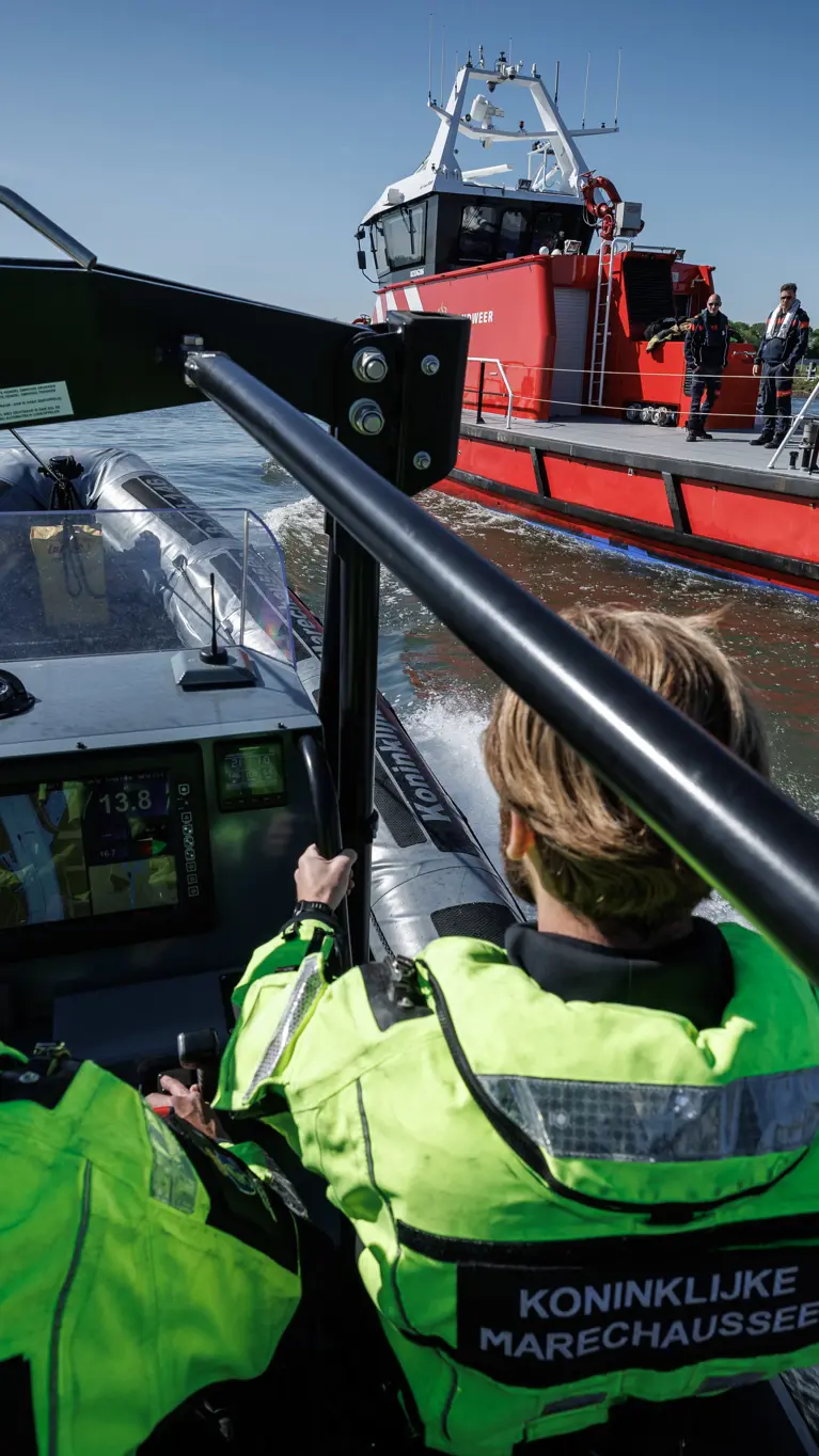 Marechaussees in een vaartuig met een boot van de brandweer op de achtergrond.