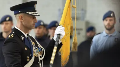 Luitenant-generaal Roger Costongs, gekleed in ceremonieel tenue, houdt de oranje KMar-standaard vast. 