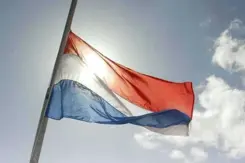 Nederlandse vlag wappert halfstok. 
