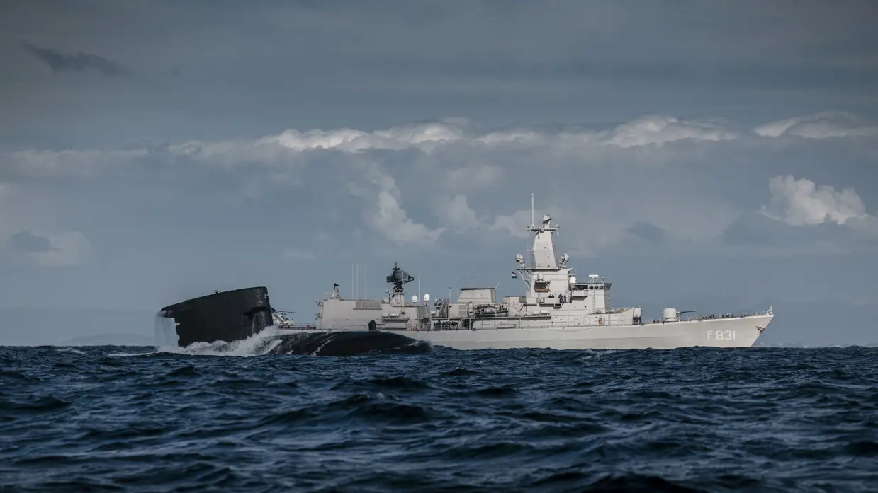 Marineschip en onderzeeboot ervoor op zee.