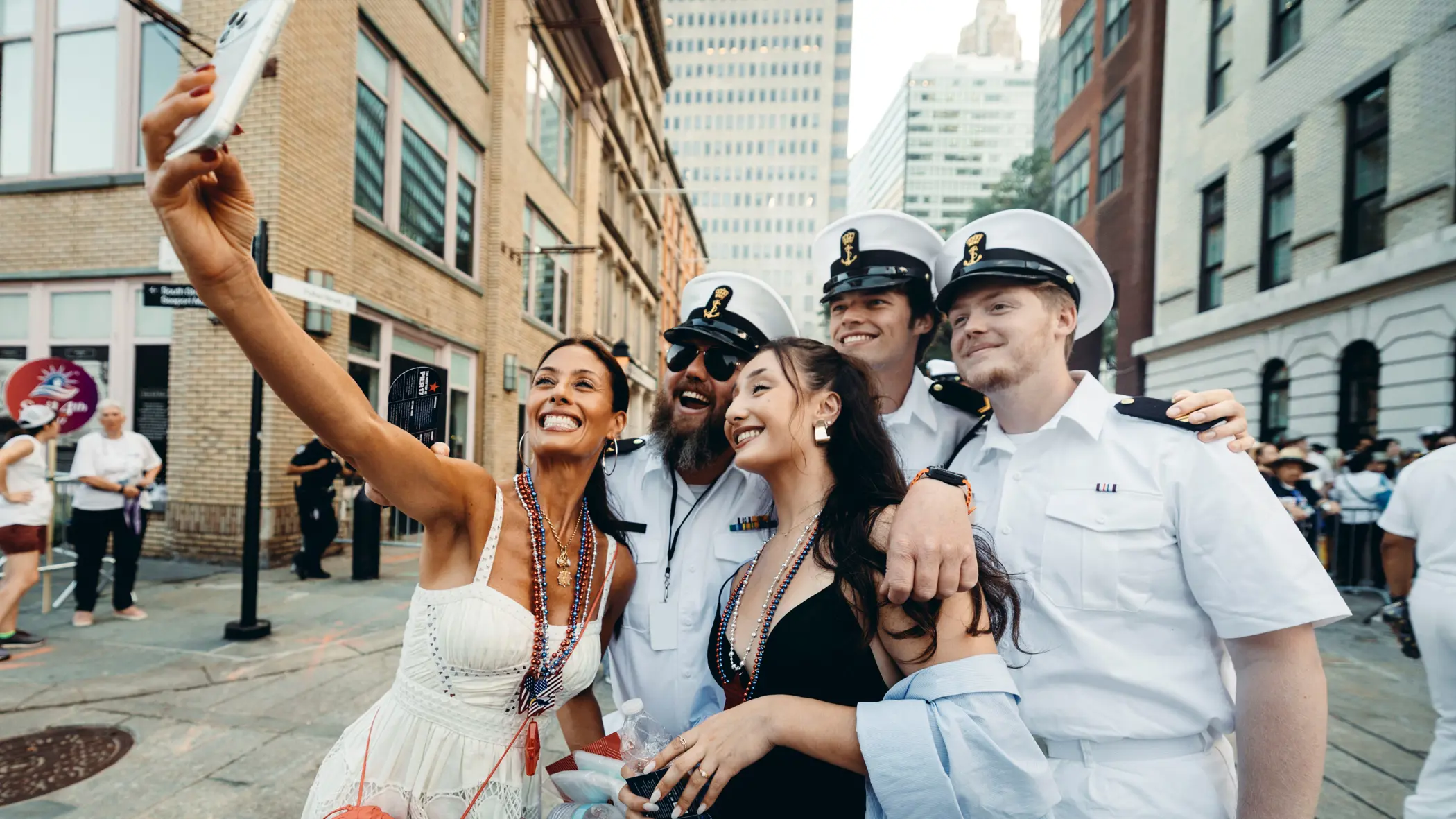 Bemanningsleden in wit uniform laten zich fotograferen met twee New Yorkse dames.