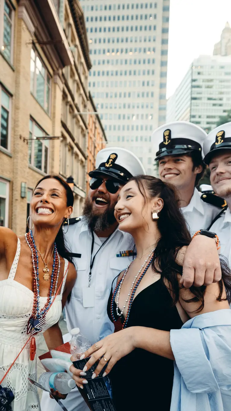 Bemanningsleden in wit uniform laten zich fotograferen met twee New Yorkse dames.