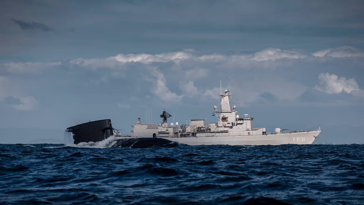 Marineschip en onderzeeboot ervoor op zee.