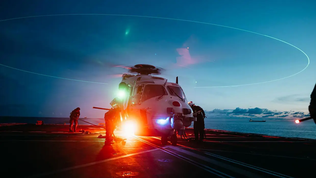 Een helikopter staat klaar om op te stijgen vanaf het schip in het schemerlicht.