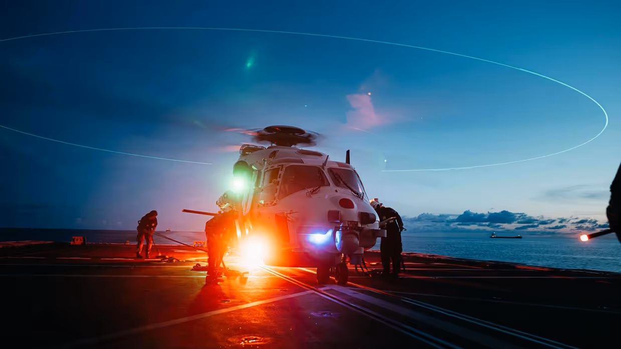 Een helikopter staat klaar om op te stijgen vanaf het schip in het schemerlicht.