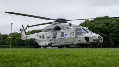 Een Chinook stijgt op boven een veld, met aan een lange kabel de Nederlandse vlag