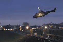 Helikopter bij schemer boven bewoond gebied.