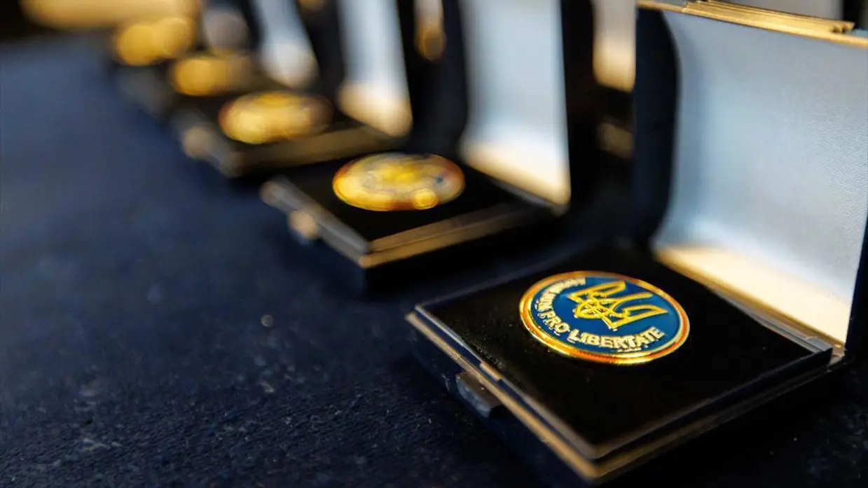 Rij opengeklapte doosjes met daarin ieder een blauw-gele medaille.