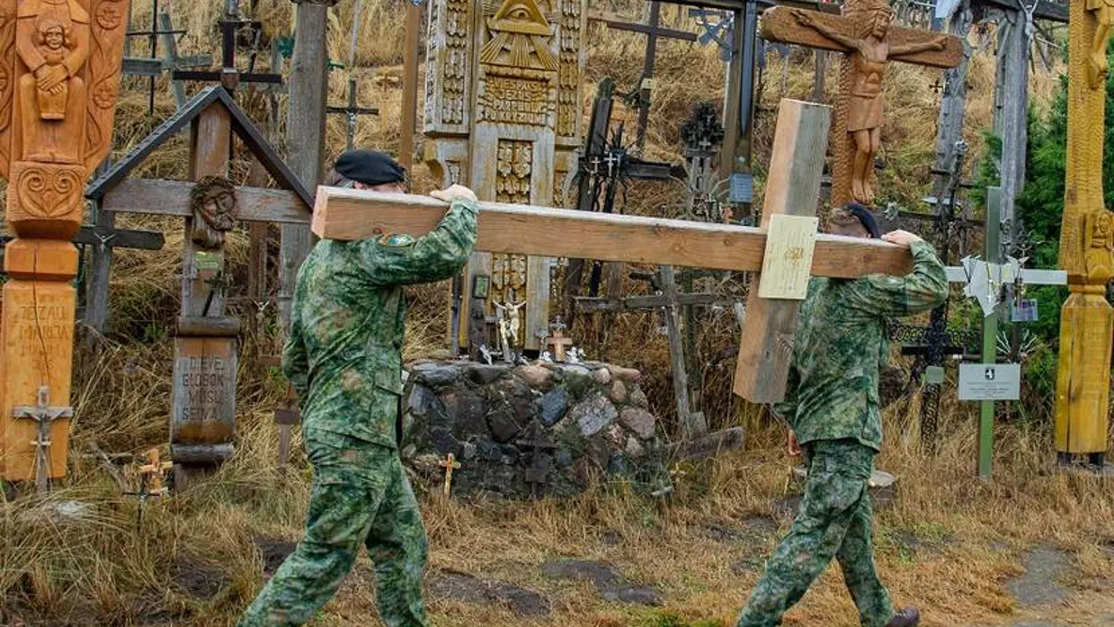 2 militairen dragen groot houten kruis.