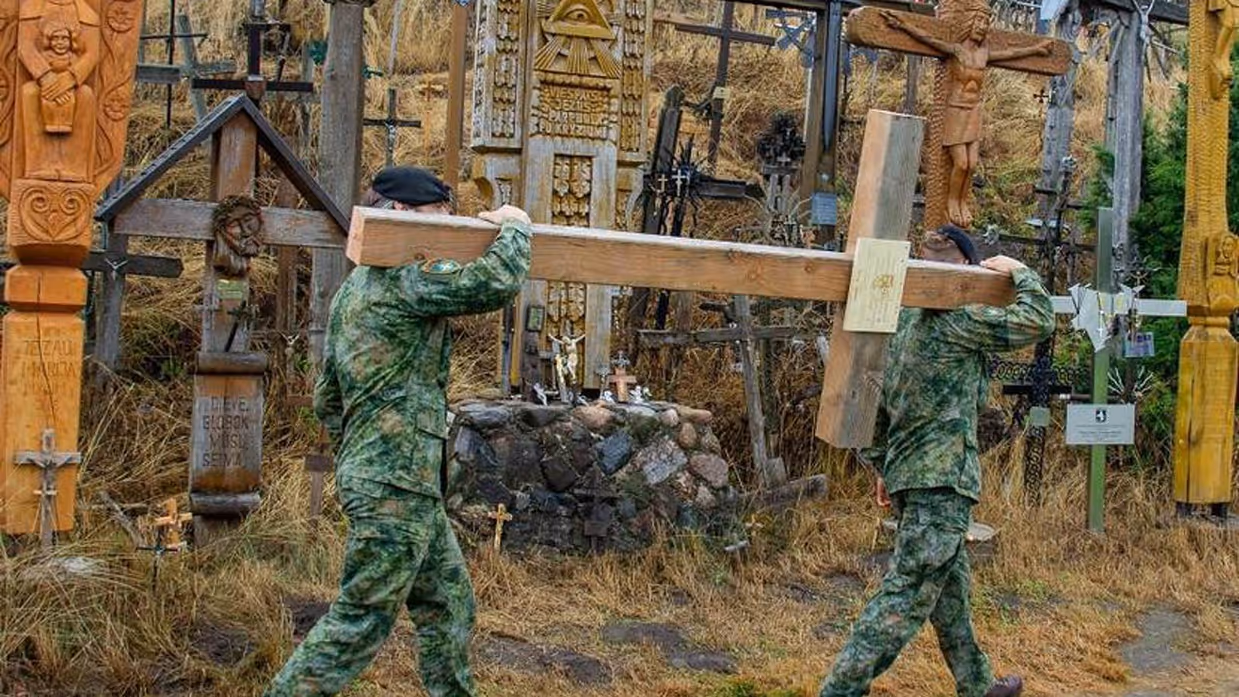 2 militairen dragen groot houten kruis.