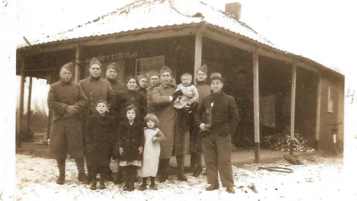 Historische groepsfoto militairen met kinderen.
