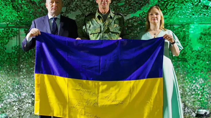 Drie personen houden een Oekraiense vlag vast.