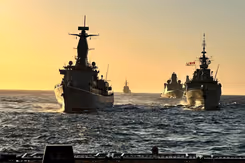 Marineschepen varen achter elkaar op zee.