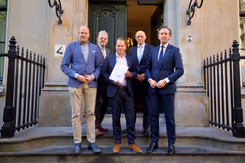 De staatssecretaris poseert met 4 mannen op de trap van het ministerie.