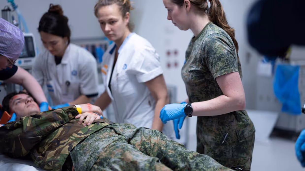 Militair in bed met zorgpersoneel eromheen,