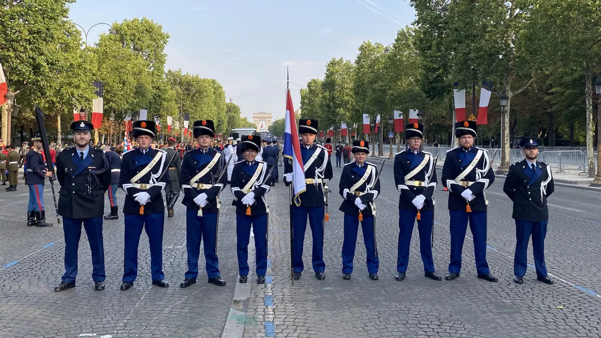 Negen marechaussees, van wie zeven in ceremonieel tenue, staan op een rij.