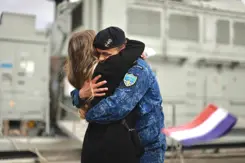 Marineman omhelst vrouw. Op de voorgrond Nederlands vlaggetje.