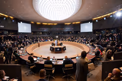 Defensieministers van de NAVO vergaderen aan een cirkelvormige tafel.