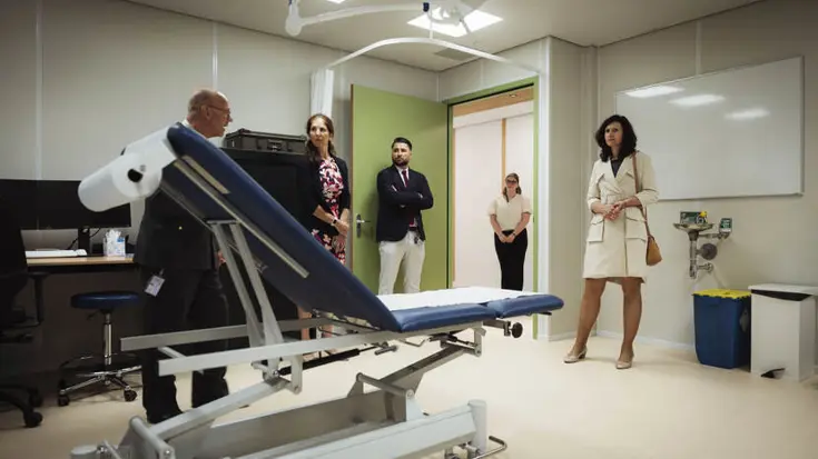 5 personen bekijken nieuwe behandelkamer met behandelstoel in het midden.