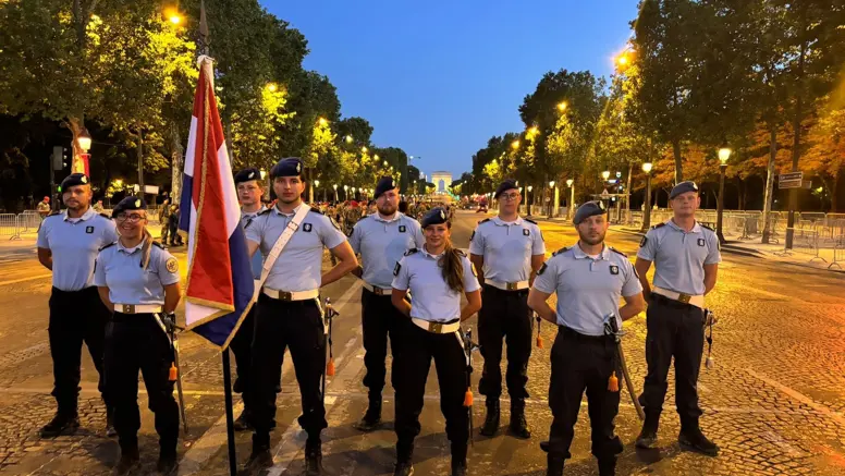 Een groep marechaussees staat in het lantaarnlicht in Parijs. Een persoon houdt de Nederlandse vlag vast.