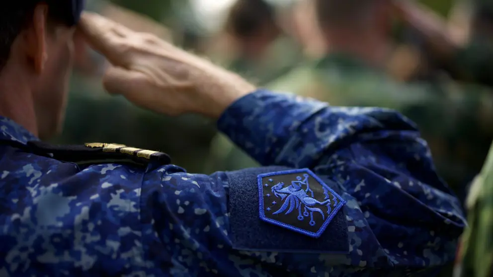 Een militair met het logo van JFC op het uniform brengt een groet uit.