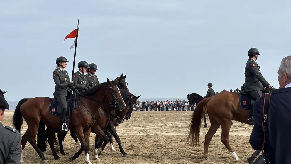 De ruiters met hun paarden op het strand. 