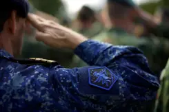 Een militair met het logo van JFC op het uniform brengt een groet uit.