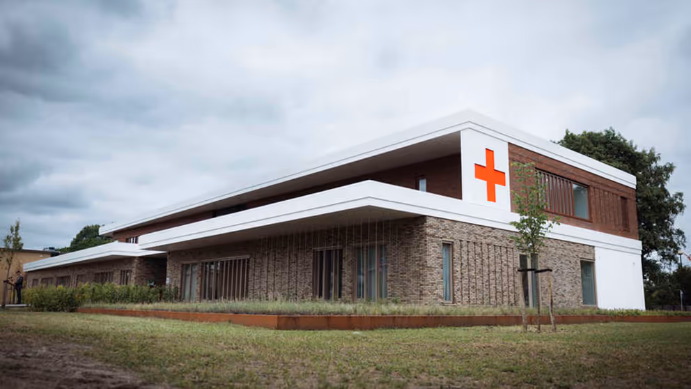 Buitenkant militair Gezondheidscentrum en Tandheelkundig Centrum met rood kruis op de buitenmuur.