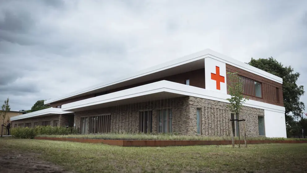 Buitenkant militair Gezondheidscentrum en Tandheelkundig Centrum met rood kruis op de buitenmuur.