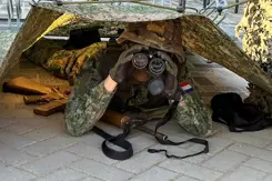 Militair met verrekijker onder tentdoek.