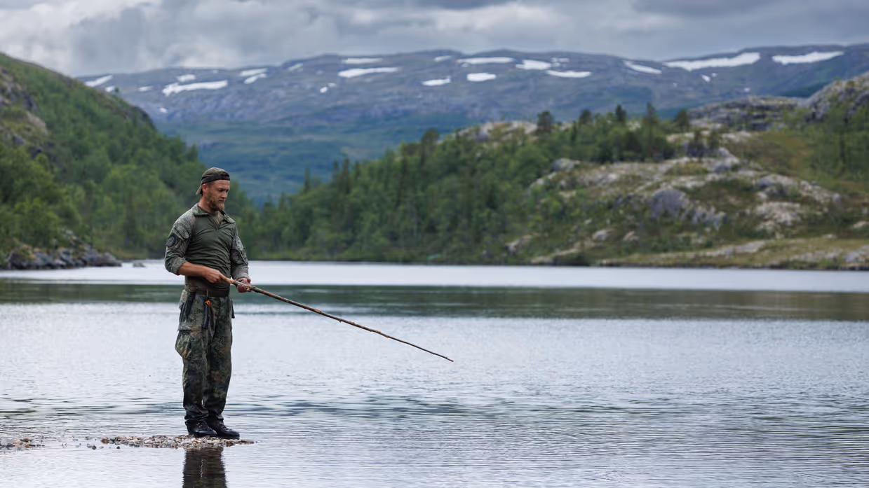 Militair die staat te vissen bij een rivier.