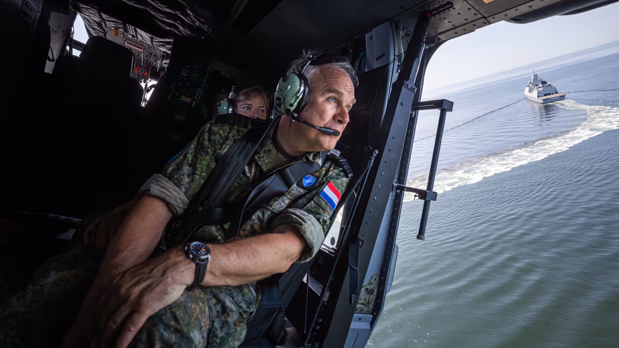 Militair kijkt naar buiten vanuit helikopter.
