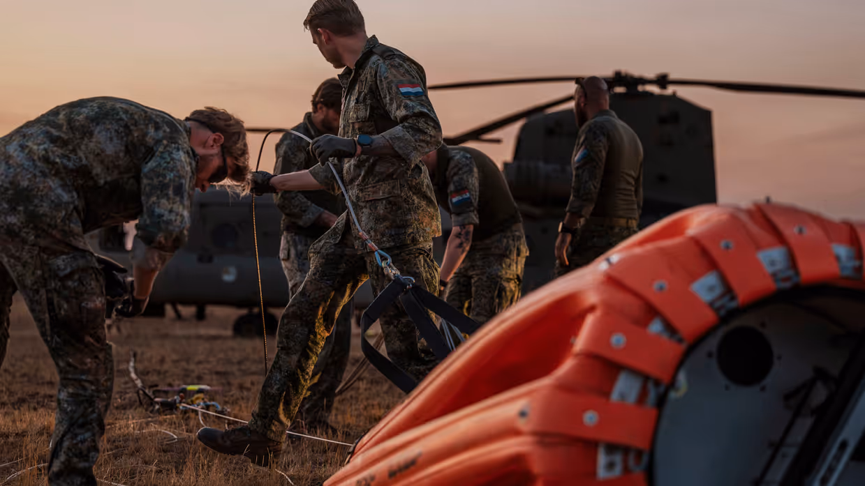 Militairen controleren kabels bevestigd aan een helikopter