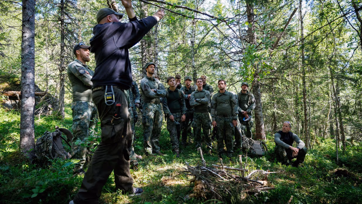 Instructeur geeft instructies aan militairen in bosgebied.