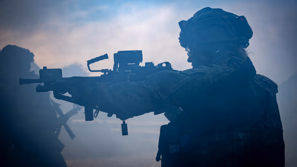 Een militair die met een geweer paraat staat.