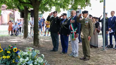 Militairen in uniform salueren en een man in pak met sjerp bij een krans.