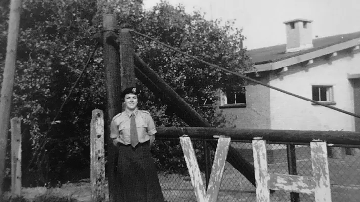 Militair van het Vrouwen Hulpkorps bij een hek
