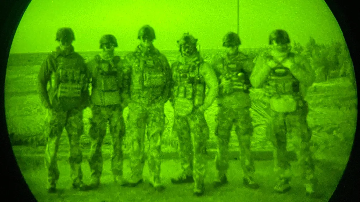 Een zestal militairen poseert samen voor een nachtlens.
