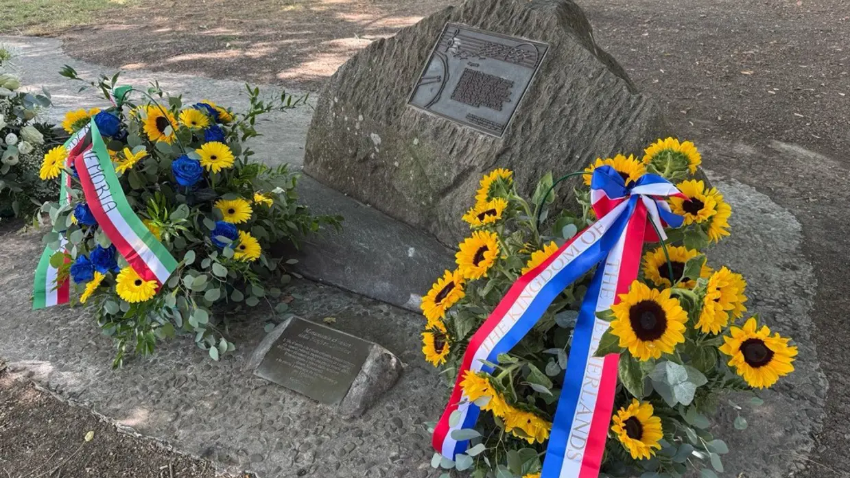 een gedenksteen met bloemen.