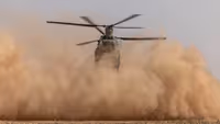 Chinook-transporthelikopter maakt stofwolk vlak boven de grond.