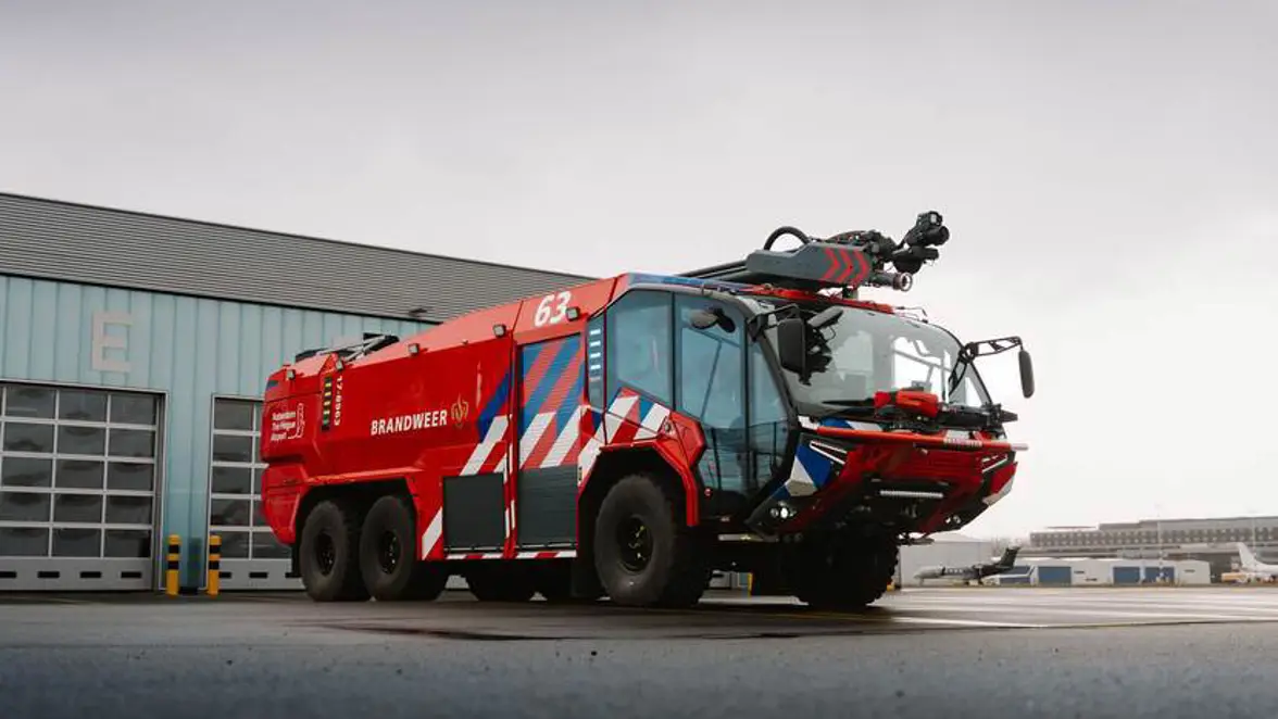 Brandweervoertuig met veel rood, blauwwitte strepen en grote glazen cabine. 