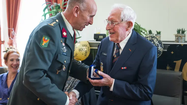 Een militair feliciteert een 100-jarige veteraan.