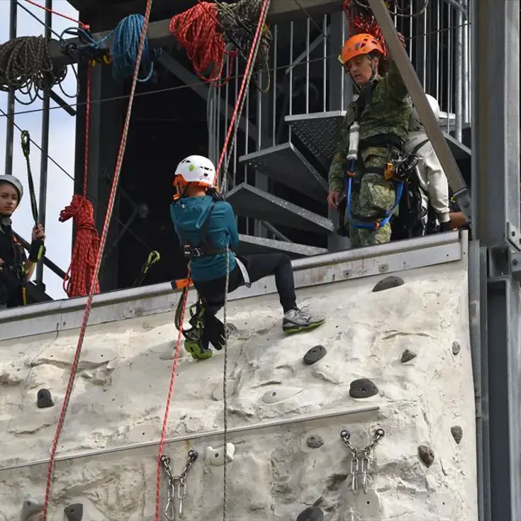 Kinderen abseilen terwijl een militair hen in de gaten houdt.