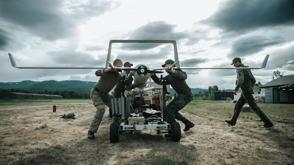 4 militairen aan het werk bij de lanceerinstallatie van een onbemand verkenningsvliegtuig.