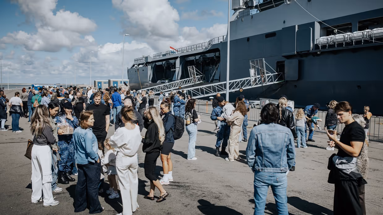 Familie en vrienden zwaaien de bemanning uit op de kade.