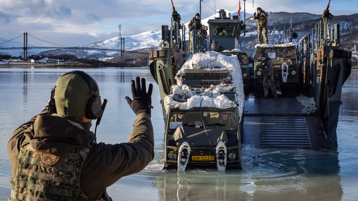 Militair begeleidt voertuig vanaf landingsvaartuig.