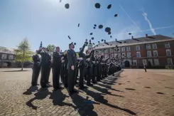 Cadetten van de KMA gooien hun hoofddeksels in de lucht.