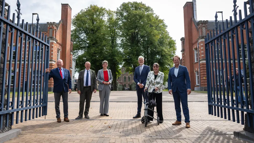 De ondertekenaars staan tussen de poorten van de kazerne. 
