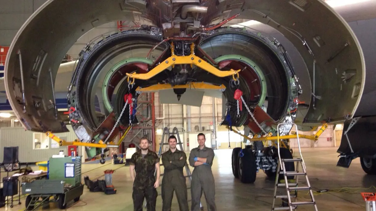 Technici staan onder de geopende motorgondel van een KDC-10 in een onderhoudshangar.